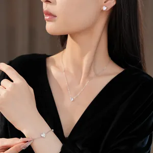 Detail view of model wearing minimalist zircon heart necklace, earrings, and bracelet