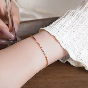 Detail view of a dainty rainbow zircon 18k gold plated adjustable bracelet on female wrist