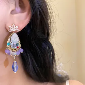 Detailed view of a vintage court style drop earring with colorful crystals on a model.