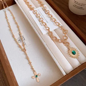 Detailed view of vintage gold cross and green stone pendant necklaces in a box