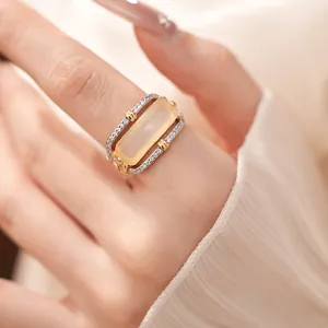 Close-up of elegant gold and silver hollow ring with rectangular yellow stone and zircons