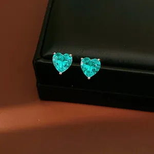 Close-up view of elegant heart-shaped turquoise zircon stud earrings on black display