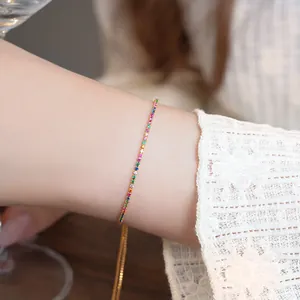 Close-up detail of colorful zirconia stones on a delicate 18k gold plated drawstring bracelet.