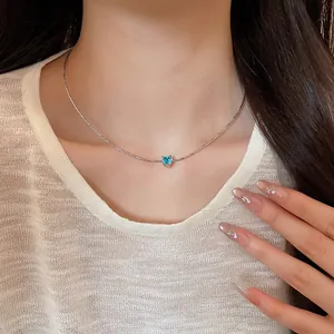 Detail shot of a delicate silver choker with a sparkling blue heart zircon pendant.