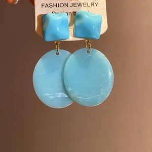 Detailed view of vintage blue resin earrings with square and oval geometric pendants.