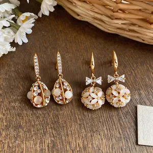 Detailed macro view of 14k gold plated earrings featuring cat's eye stones and crystals.
