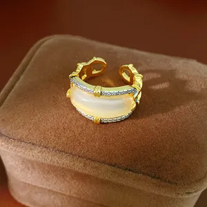 Close-up of a gold-plated ring with zircon pavé and a cream cat-eye stone