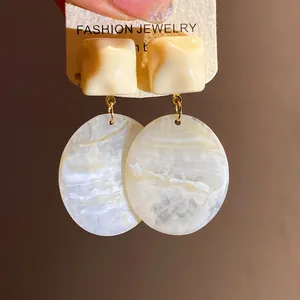Macro detail of retro resin square stud earrings with marble textured oval pendants