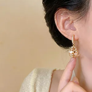 Close-up of 14k gold-plated waterdrop earrings with cat's eye stone and crystals