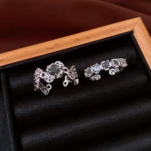 Détail macro de bagues ouvertes minimalistes en argent avec pierres vertes dans une boîte à bijoux