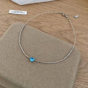 Close-up of blue heart zircon pendant necklace with twisted silver chain