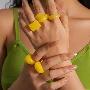 Detail close-up of 5-piece bright yellow resin geometric rings set on model's hand