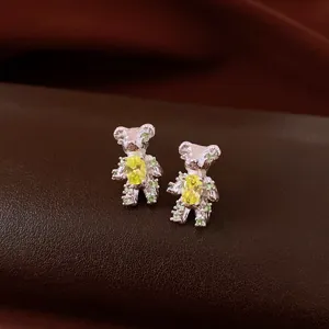 Macro view of silver bear stud earrings decorated with yellow and green zircon stones.