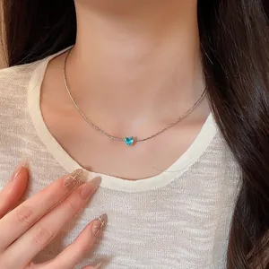 Close-up of a French style necklace with a blue heart zircon pendant worn by a model.