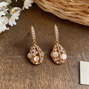 Macro view of 14k gold-plated earrings with cat's eye stones and sparkling crystals.