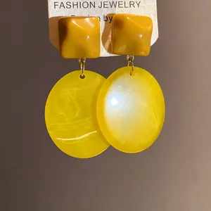 Close-up of retro Maillard style resin earrings with brown square and yellow oval drops