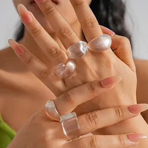 Close-up macro detail of a five-piece set of translucent resin geometric rings on hands