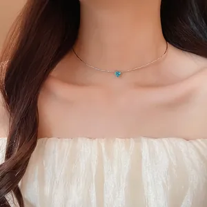 Detailed view of a French style blue heart zircon pendant necklace worn by an elegant model