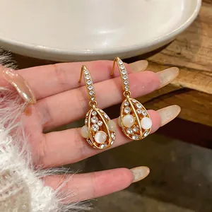 Close-up of 14k gold plated drop earrings with cat's eye stones and crystals