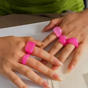 Detailed close-up showing a five-piece set of vibrant pink resin geometric rings on hands