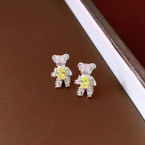 Macro detail of exquisite silver teddy bear stud earrings set with vibrant yellow and green zircons.