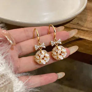 Macro view of 14k gold plated drop earrings with crystal bow and cat's eye flower