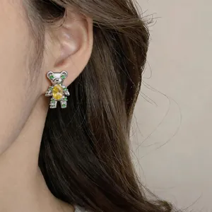 Detailed view of a retro bear stud earring with sparkling yellow zircon on model's ear