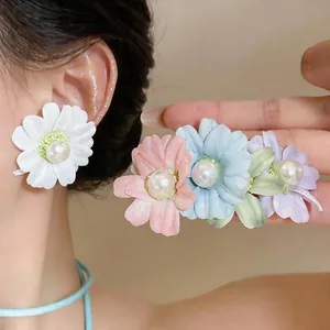 Close-up of elegant fabric flower stud earrings featuring white pearls in pastel colors