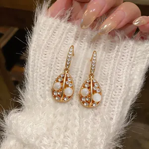 Detail of 14k gold plated teardrop earrings with cat's eye stone and rhinestones