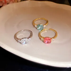 Elegant zircon square open rings in pink, blue, and clear colors on white ceramic plate
