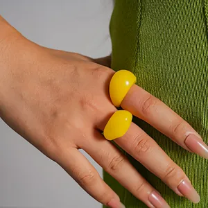 Detailed close-up view of bold yellow resin geometric rings worn on a model's hand