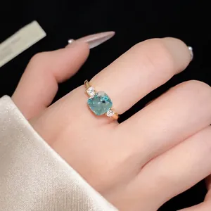 Elegant gold open ring featuring a cushion-cut blue zircon flanked by clear stones