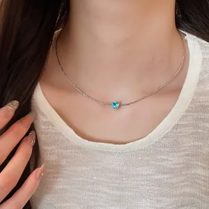 Detailed shot of French style blue heart zircon pendant necklace on female model neck