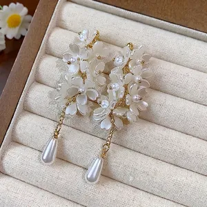 Elegant French style white flower tassel earrings with teardrop pearls on display tray