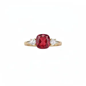 Elegant gold ring featuring a cushion-cut red gemstone and clear side accents on white.