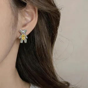 Close-up of a zircon bear stud earring with yellow and green stones on model's ear