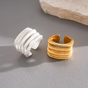 Vista detallada de anillos abiertos multicapa texturizados en acabados plata y oro.