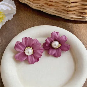Elegant purple fabric flower stud earrings with pearl centers displayed on a plate