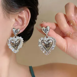 Detailed macro view of vintage silver ruffled heart earrings with delicate floral motifs