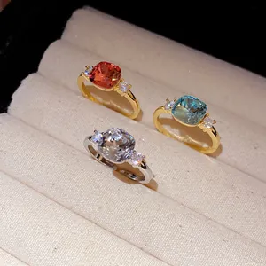 Detail of three colorful square zircon open rings displayed in a beige jewelry box.