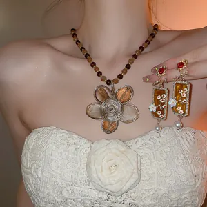 Vista dettagliata del set di collana e orecchini floreali vintage con ambra e perle.