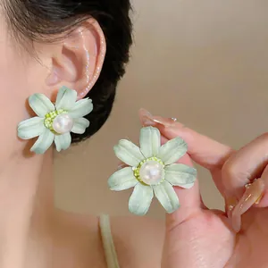 Detailed close-up view of light green fabric flower stud earrings with central pearls.