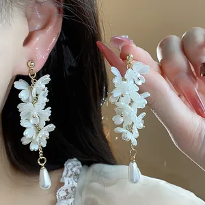Close-up detail of elegant French-style white flower tassel earrings with teardrop pearls