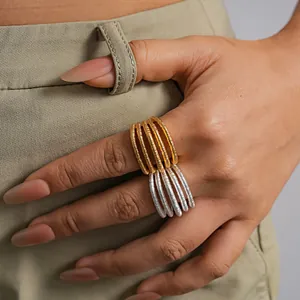 Detalle macro de anillos multicapa texturizados bañados en oro de 18k en el índice del modelo.