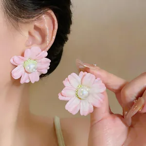 Close-up of pink fabric flower stud earrings with pearl centers worn by model