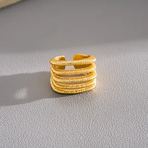 Detalle macro de un lujoso anillo abierto multicapa con textura chapado en oro de 18k