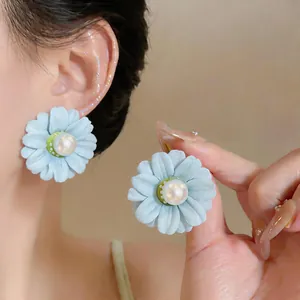 Detailed view of light blue fabric flower stud earring featuring a soft pearl center