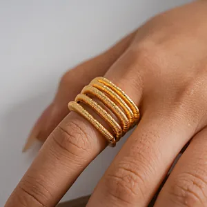 Detalle de anillo abierto multicapa con textura y lujoso acabado en baño de oro de 18 quilates