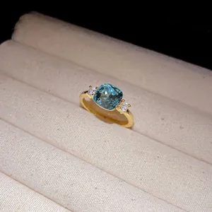 Detailed macro view of an elegant gold ring featuring a square blue zircon center stone.