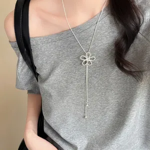 Elegant close-up of a silver zircon hollow flower pendant necklace worn on a grey t-shirt
